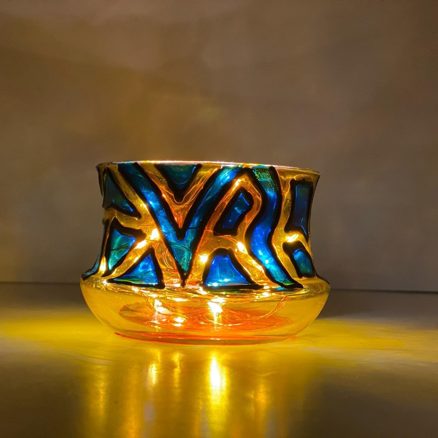 Glowing votive with golden mosaic pattern